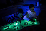 Kids using a light drawing board to create glowing art in a dark room, showcasing creativity and imagination.