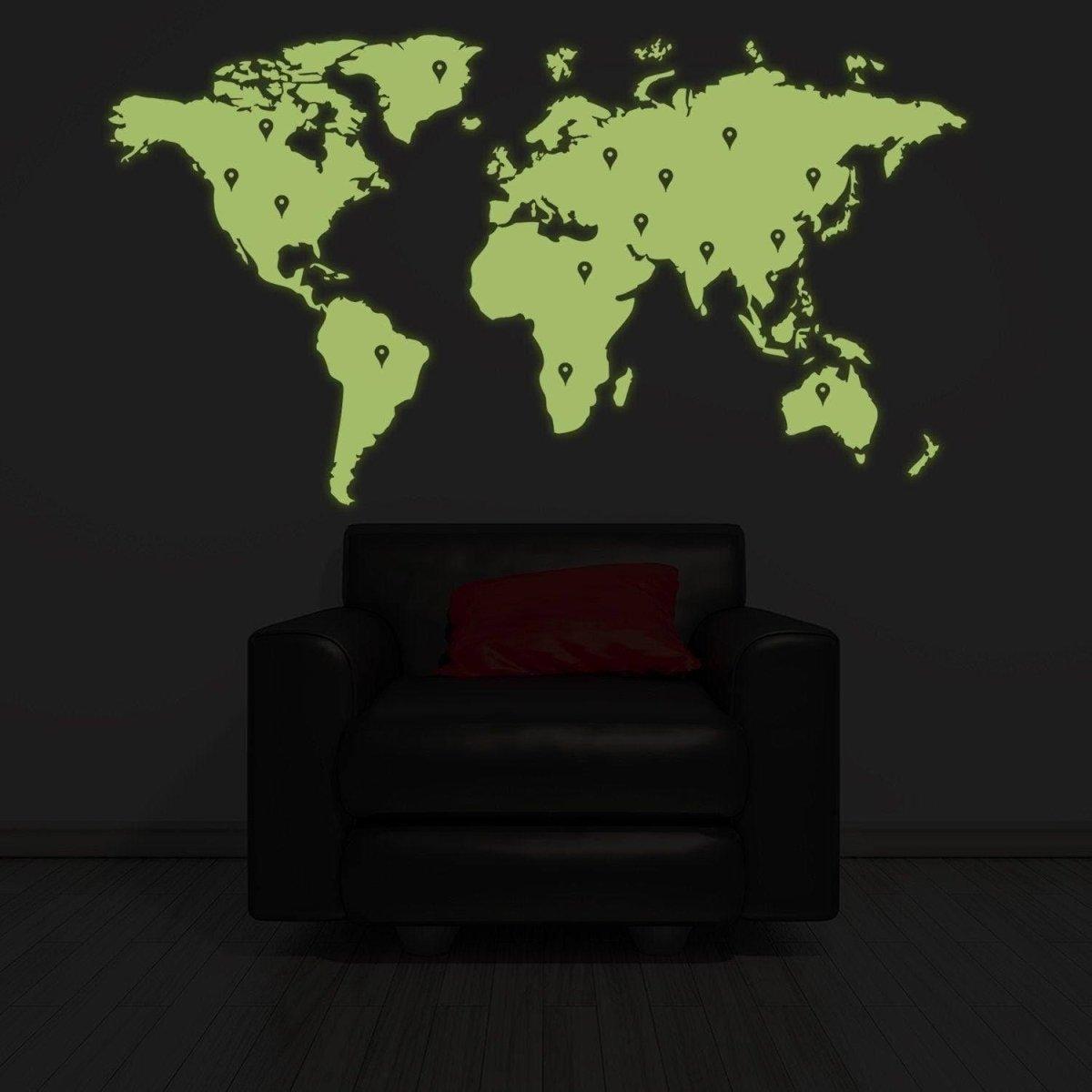 Glowing Earth wall sticker of world map in green, illuminating a dark room above a black armchair.