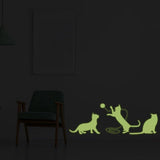 Glow-in-the-dark feline wall decal featuring playful cats in silhouette against a dark room backdrop.