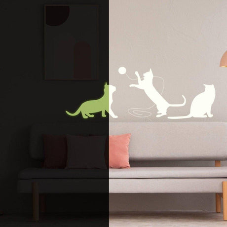 Glow in the dark cat wall decal on a beige wall above a couch with pillows.