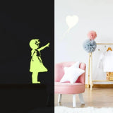 Luminescent girl wall decal glowing in the dark against a stylish room backdrop with pink chair and decor.